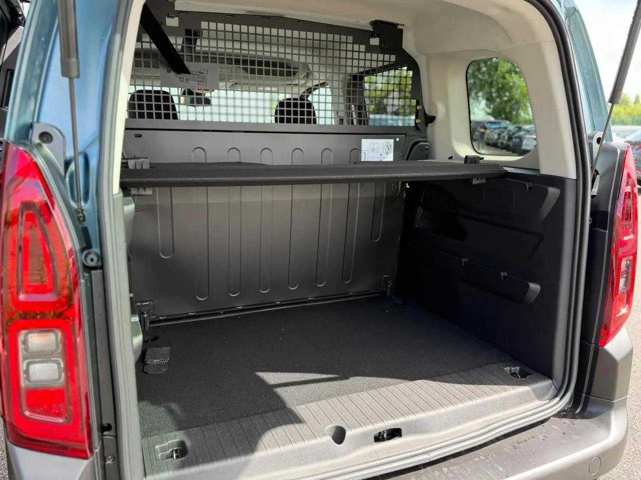 Coffre ouvert vu de l'arrière d'un Citroën Berlingo Multispace bleu Kiama avec lunette arrière ouvrante et séparation intérieure.