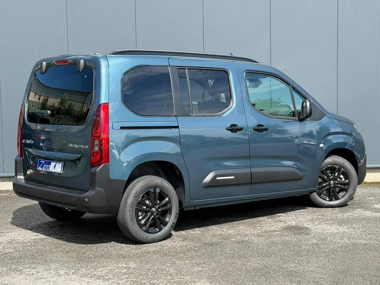 Vue 3/4 arrière droite d'un Citroën Berlingo Multispace bleu Kiama avec jantes alliage noires et lunette arrière ouvrante.