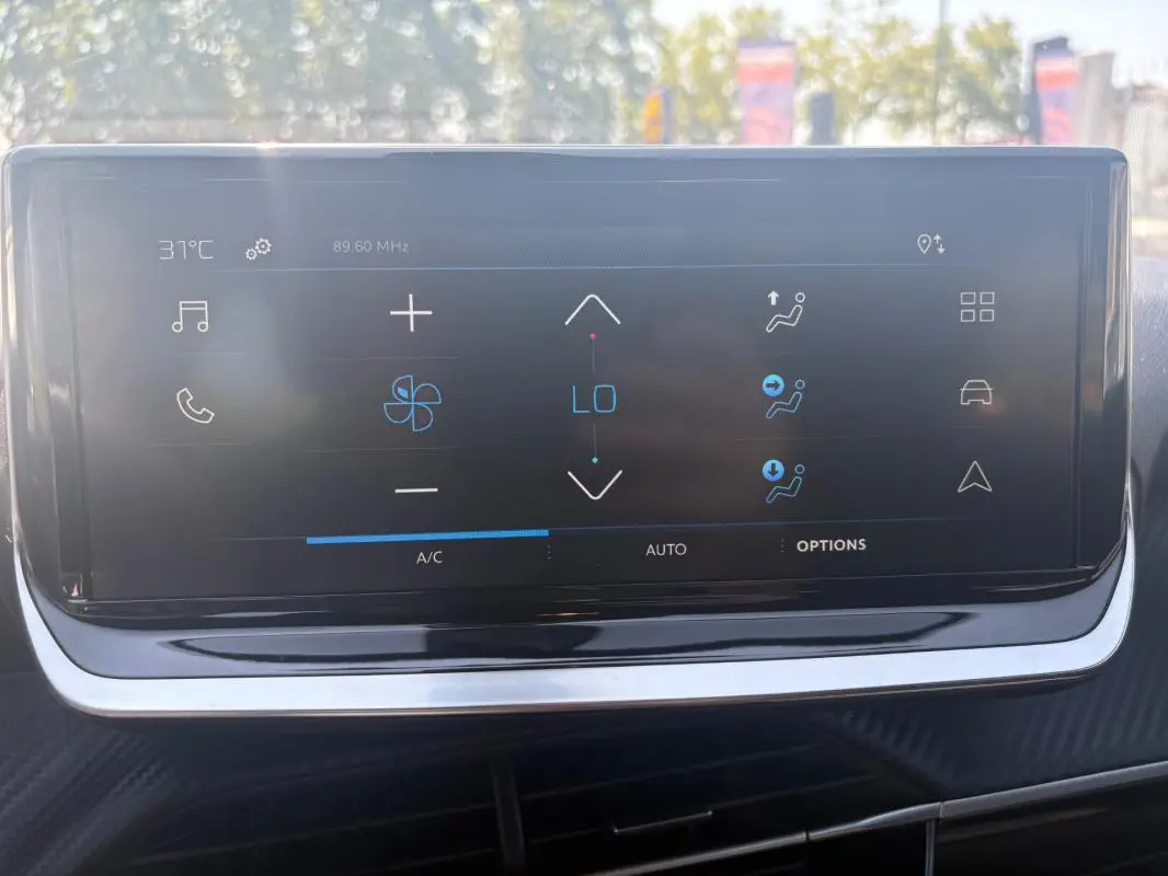 Écran tactile central du Peugeot 2008 Hybrid 145 Style 2025, affichant les commandes de climatisation en extérieur lumineux.