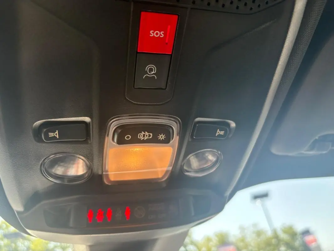 Vue en contre-plongée du plafonnier avant gris du Peugeot 2008 Hybrid 145 e-DCS6 Style 2025 avec bouton SOS rouge.