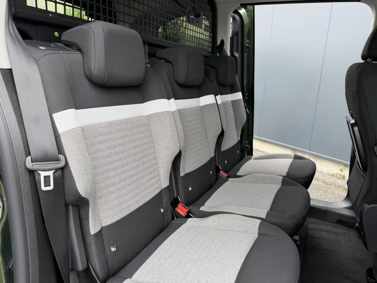 Vue latérale intérieure sur les trois sièges arrière gris et noirs du Citroën Berlingo Multispace Vert Sirkka avec porte coulissante ouverte.
