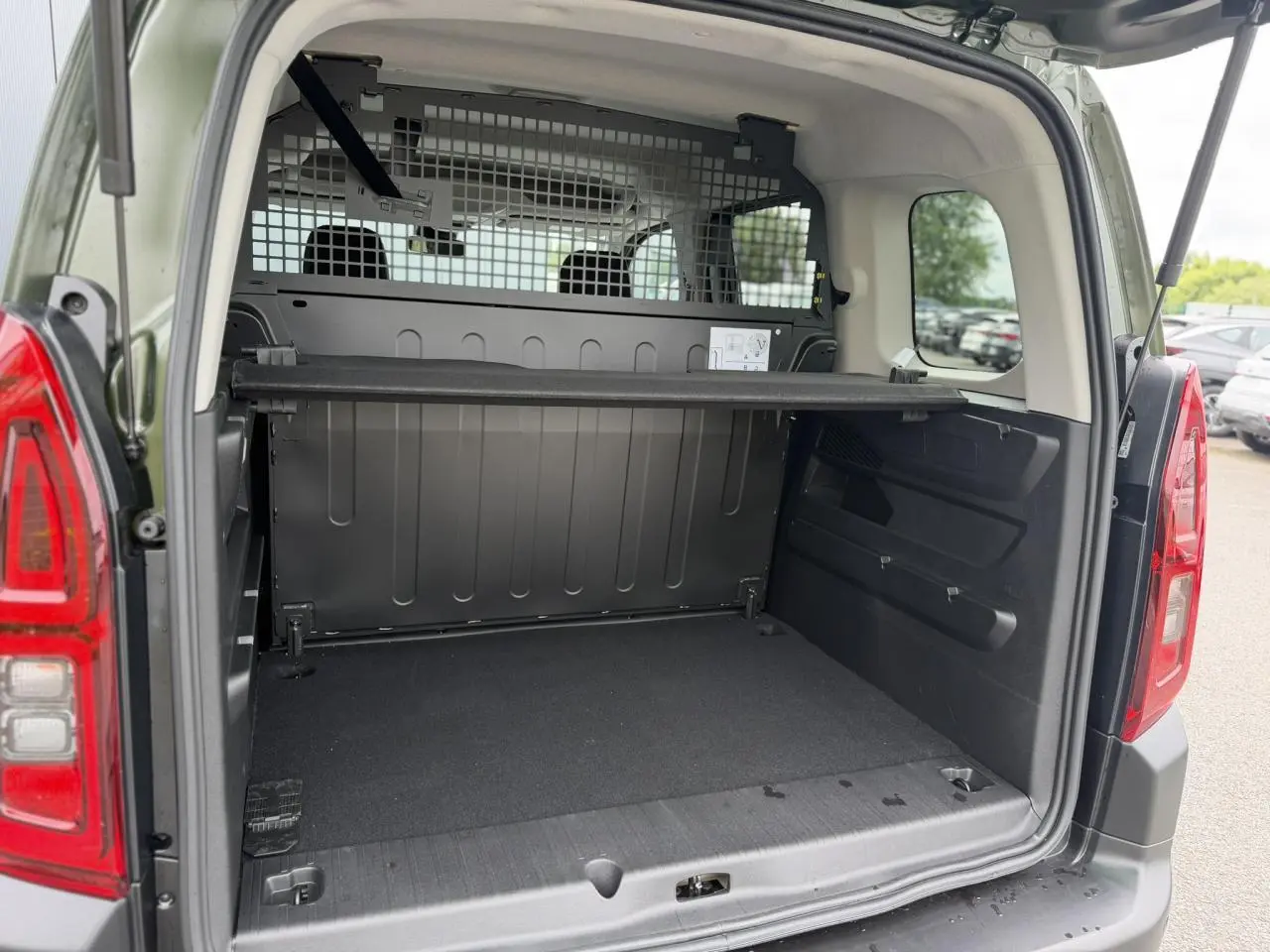 Coffre ouvert vu de l'arrière d'un Citroën Berlingo Multispace M vert Sirkka avec séparation métallique et lunette arrière ouvrante.