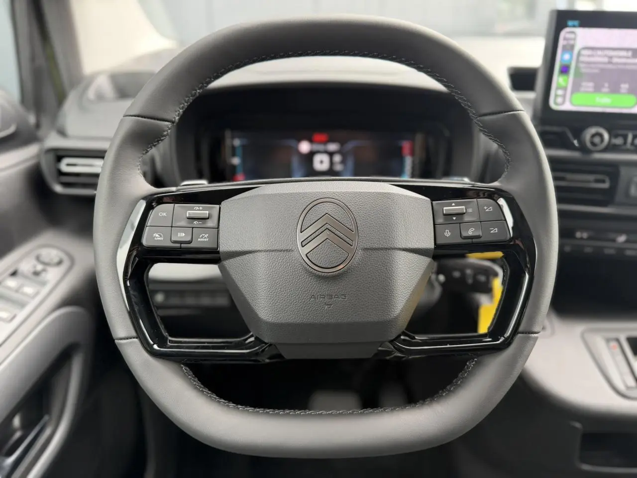 Volant cuir multifonctions Citroën Berlingo Multispace 2026 vu de face, avec commandes intégrées et tableau de bord numérique flou.