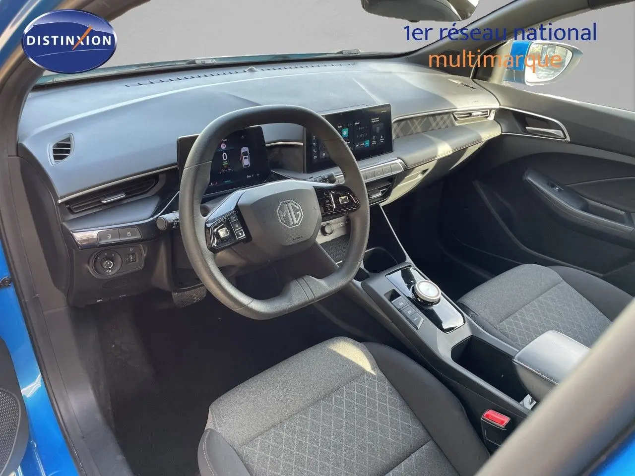 Vue intérieure côté conducteur de la MG3 2024 en bleu, avec tableau de bord digital et sièges tissu gris.