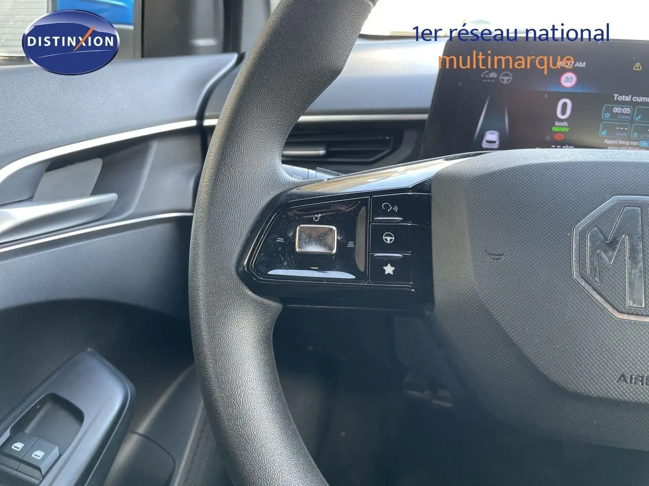 Vue rapprochée du volant MG3 2024 en tissu gris-noir, avec commandes intégrées et tableau de bord digital.