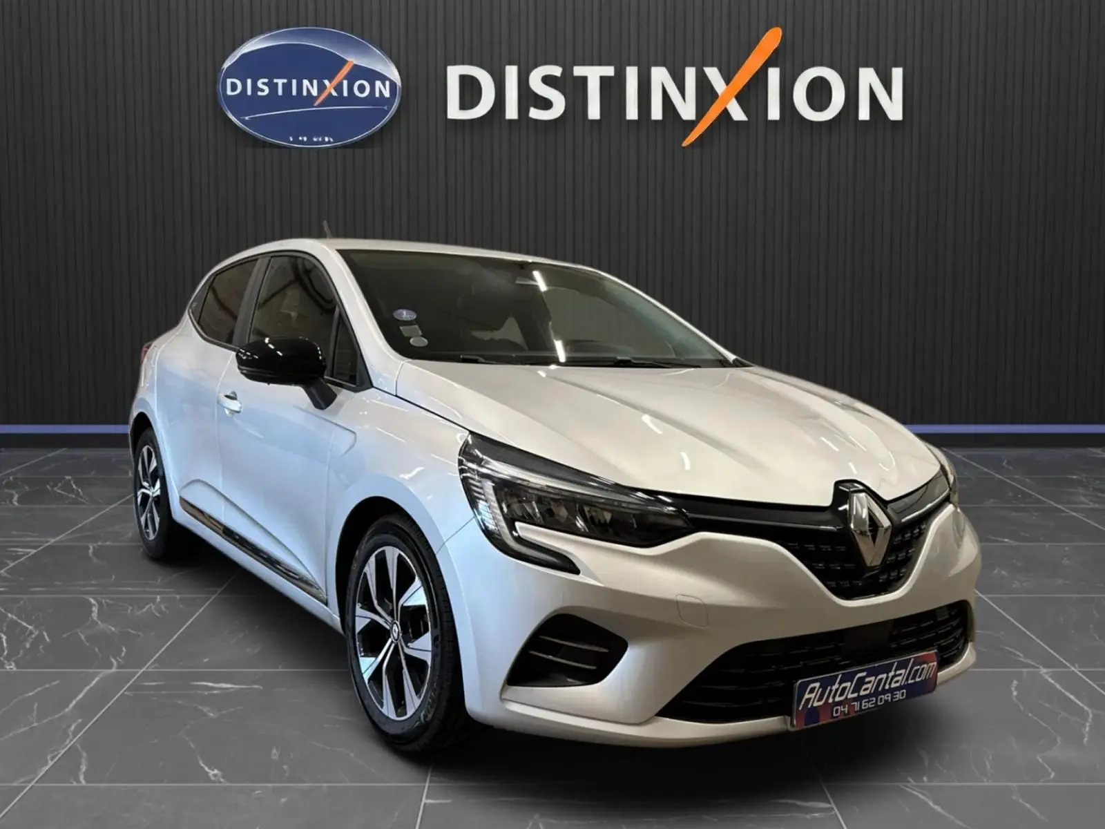 Vue 3/4 avant d'une Renault Clio V gris aluminium avec jantes biton et rétroviseurs noirs dans un showroom.