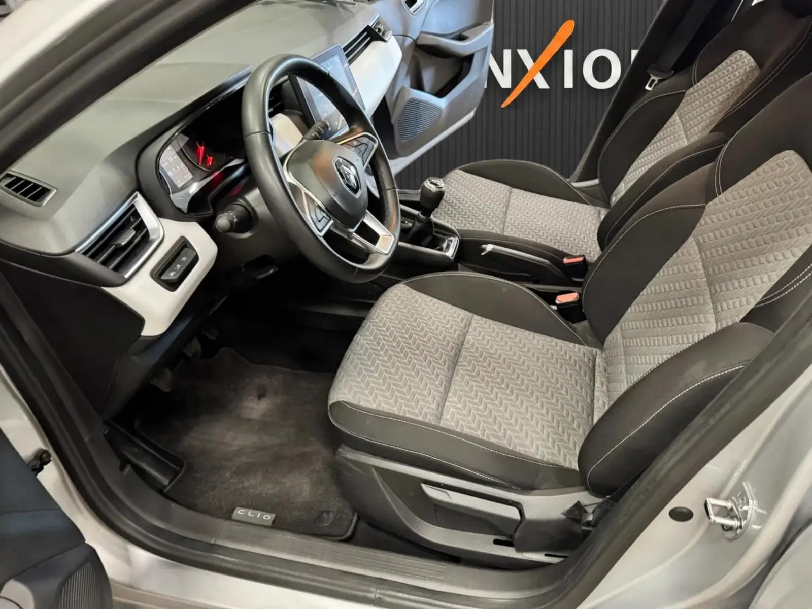 Vue intérieure côté conducteur de la Renault Clio V 1.0 SCE 65 CH Evolution avec sièges gris et volant multifonction.