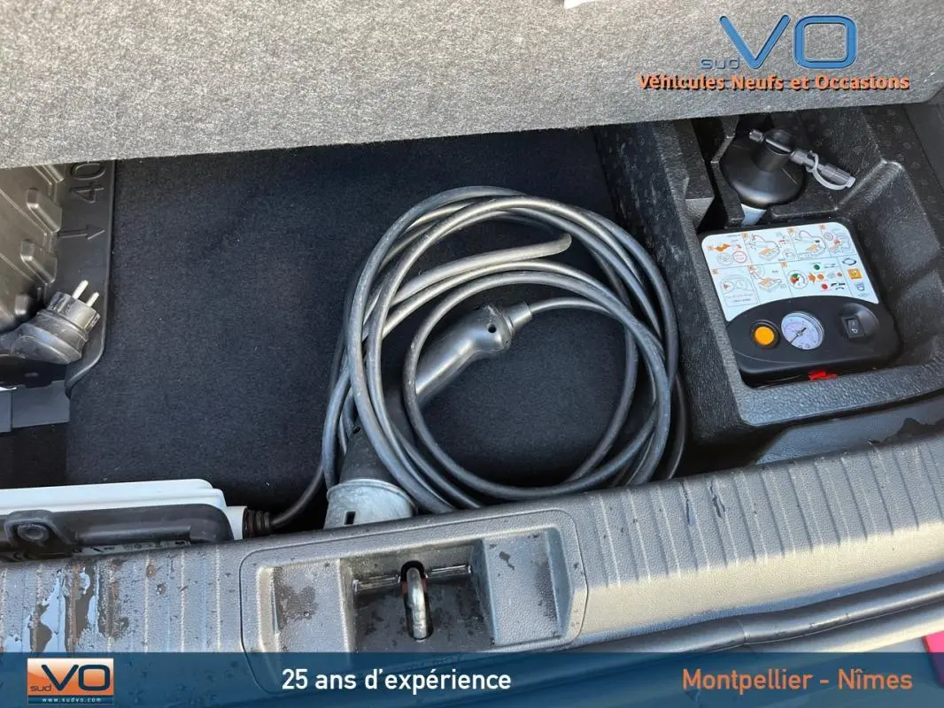 Coffre ouvert montrant le câble de recharge et kit de dépannage pneumatique du Renault Captur E-Tech Plug-in rouge.