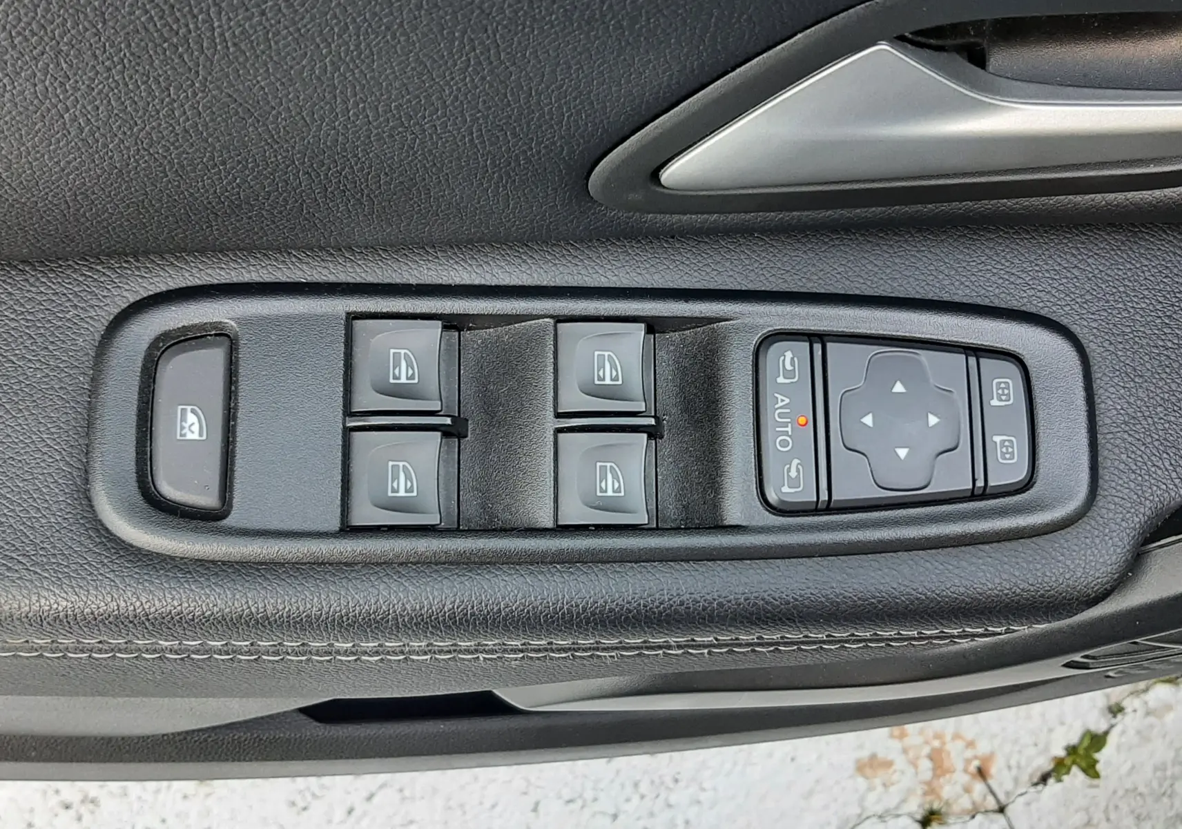 Gros plan sur les commandes des vitres et rétroviseurs côté conducteur d'un Dacia Duster 2023, intérieur noir.