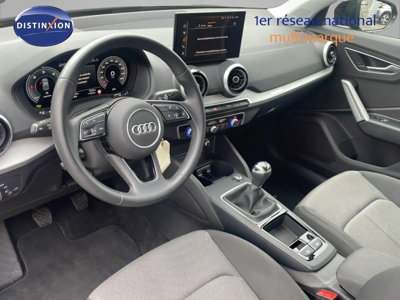 Vue intérieure côté conducteur de l'Audi Q2 30 TDI S-Line 2025, volant cuir, tableau de bord numérique et boîte manuelle.