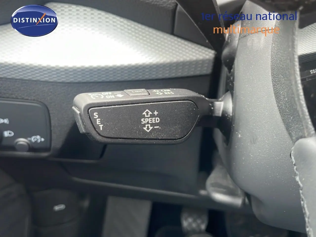 Gros plan sur la commande de régulateur de vitesse à gauche du volant dans l'habitacle noir de l'Audi Q2 30 TDI S-Line.