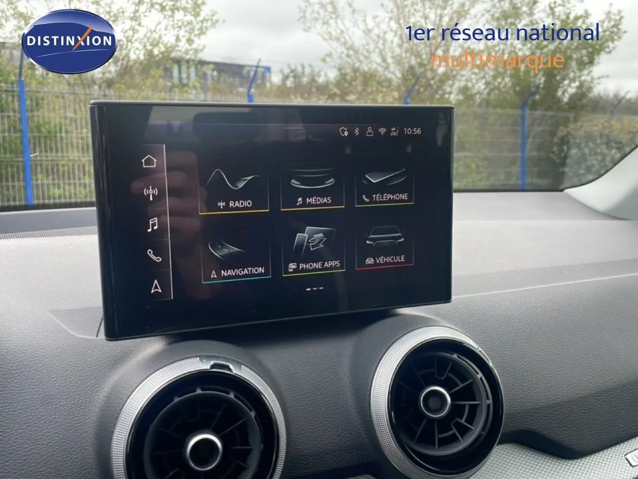 Écran tactile central avec interface multimédia, entouré de deux aérateurs ronds sur le tableau de bord d’un Audi Q2 noir.