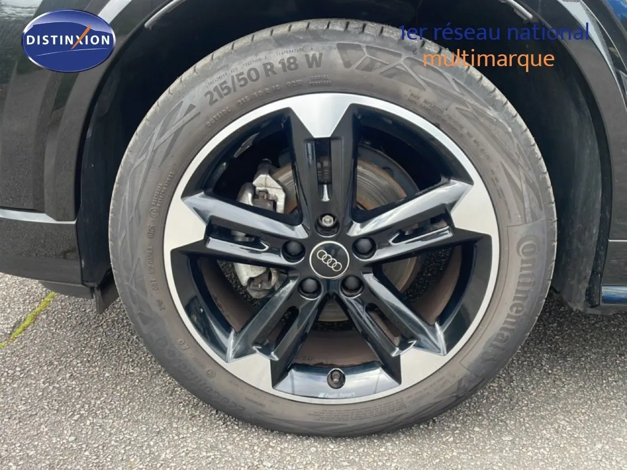 Gros plan sur la roue avant droite noire et argentée de l'Audi Q2 30 TDI S-Line 2025 avec logo Audi au centre.