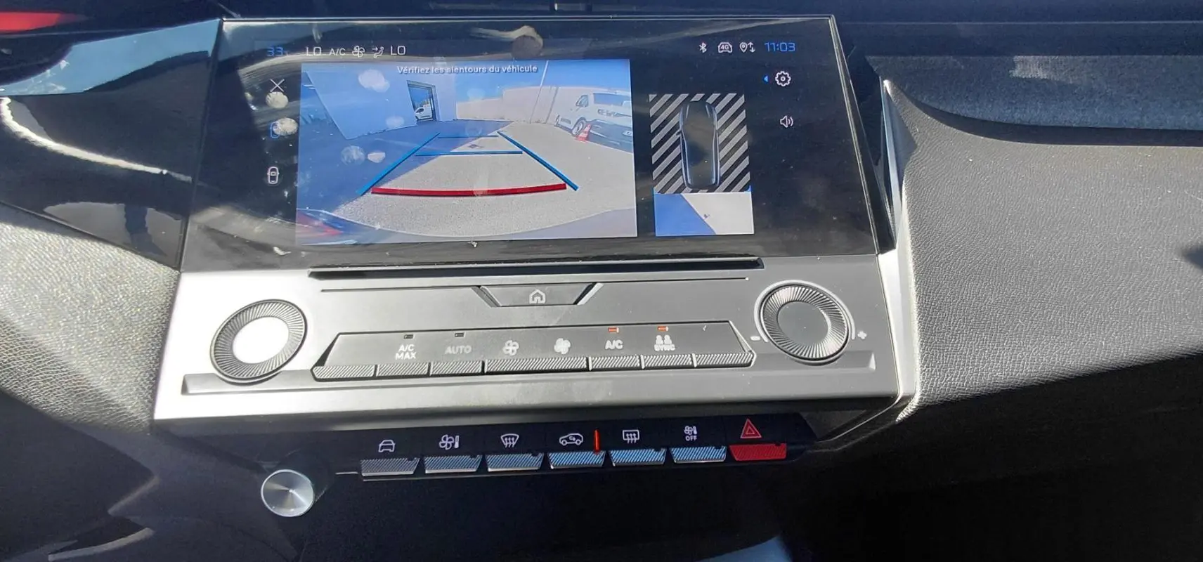 Vue rapprochée de l'écran central de la Peugeot 308 gris 2025 affichant la caméra de recul et les commandes climatisation.