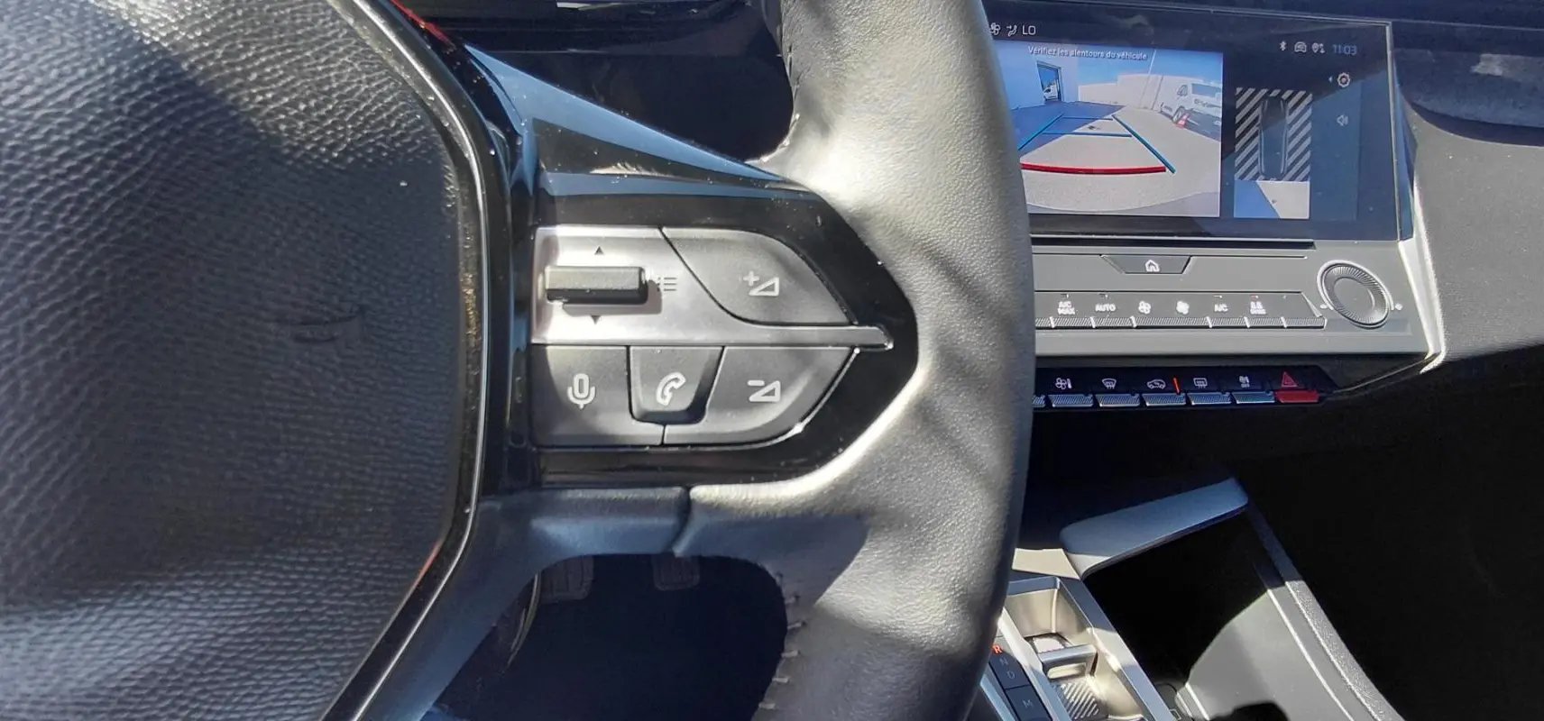 Gros plan sur le volant et l’écran central affichant la caméra de recul dans l’habitacle gris de la Peugeot 308 2025.