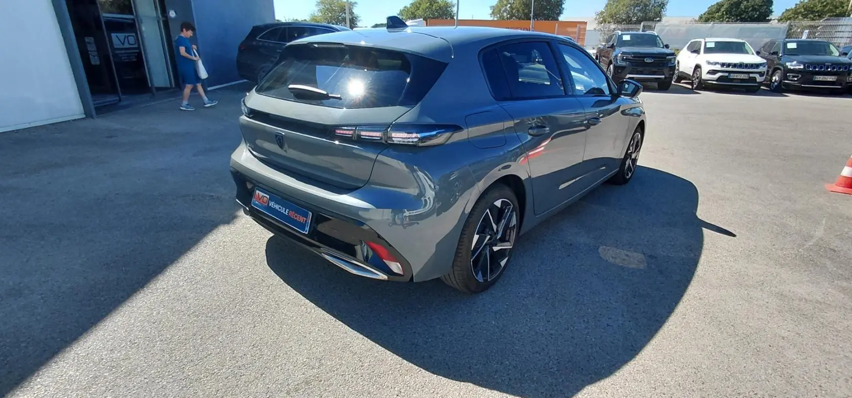 PEUGEOT 308 BlueHDi gris vue 3/4 arrière droit, avec feux arrière LED et jantes alliage distinctives.