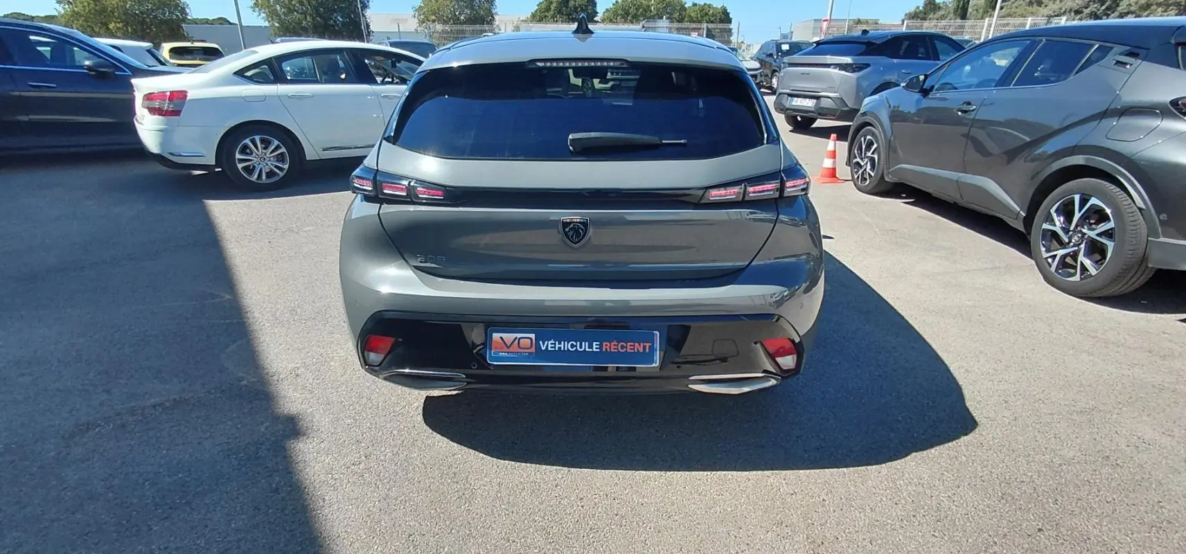 Vue arrière d'une Peugeot 308 gris métallisé 2025 avec feux LED et double sortie d'échappement visible en parking.
