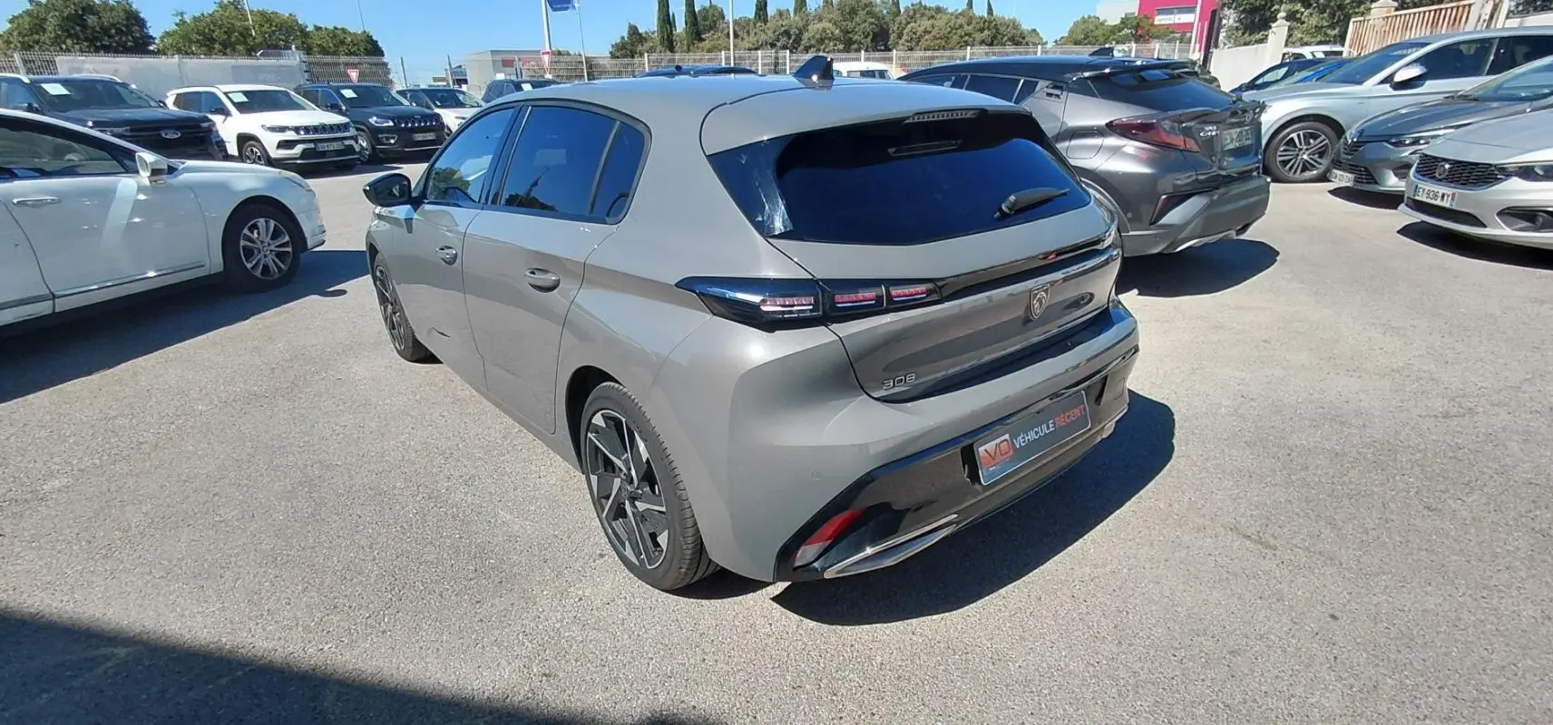 Vue 3/4 arrière droite d’une Peugeot 308 gris métallisé 2025 avec feux arrière LED et jantes alliage noires.