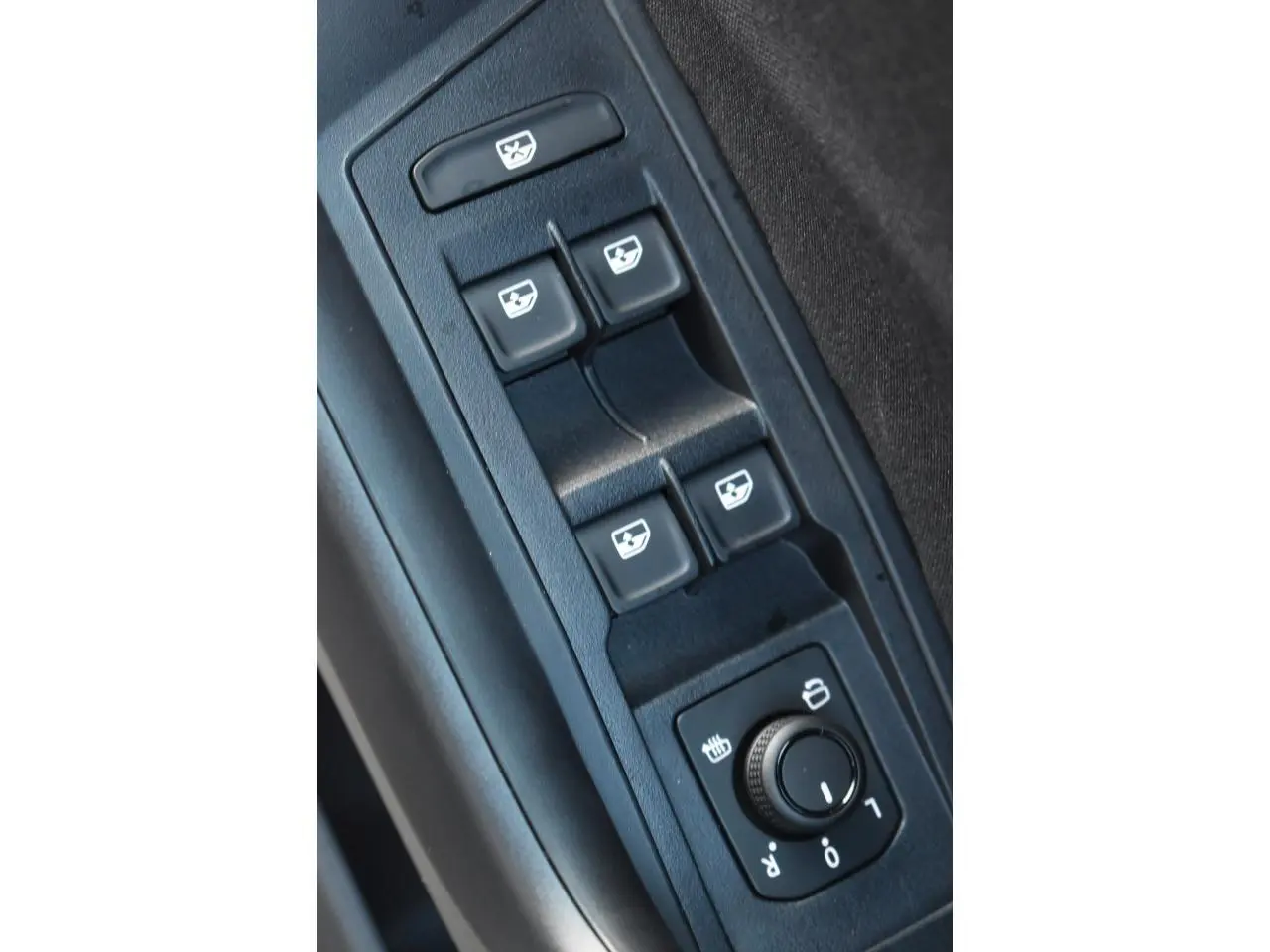 Gros plan sur les commandes des vitres et rétroviseurs du Volkswagen T-Roc 2025, intérieur noir.