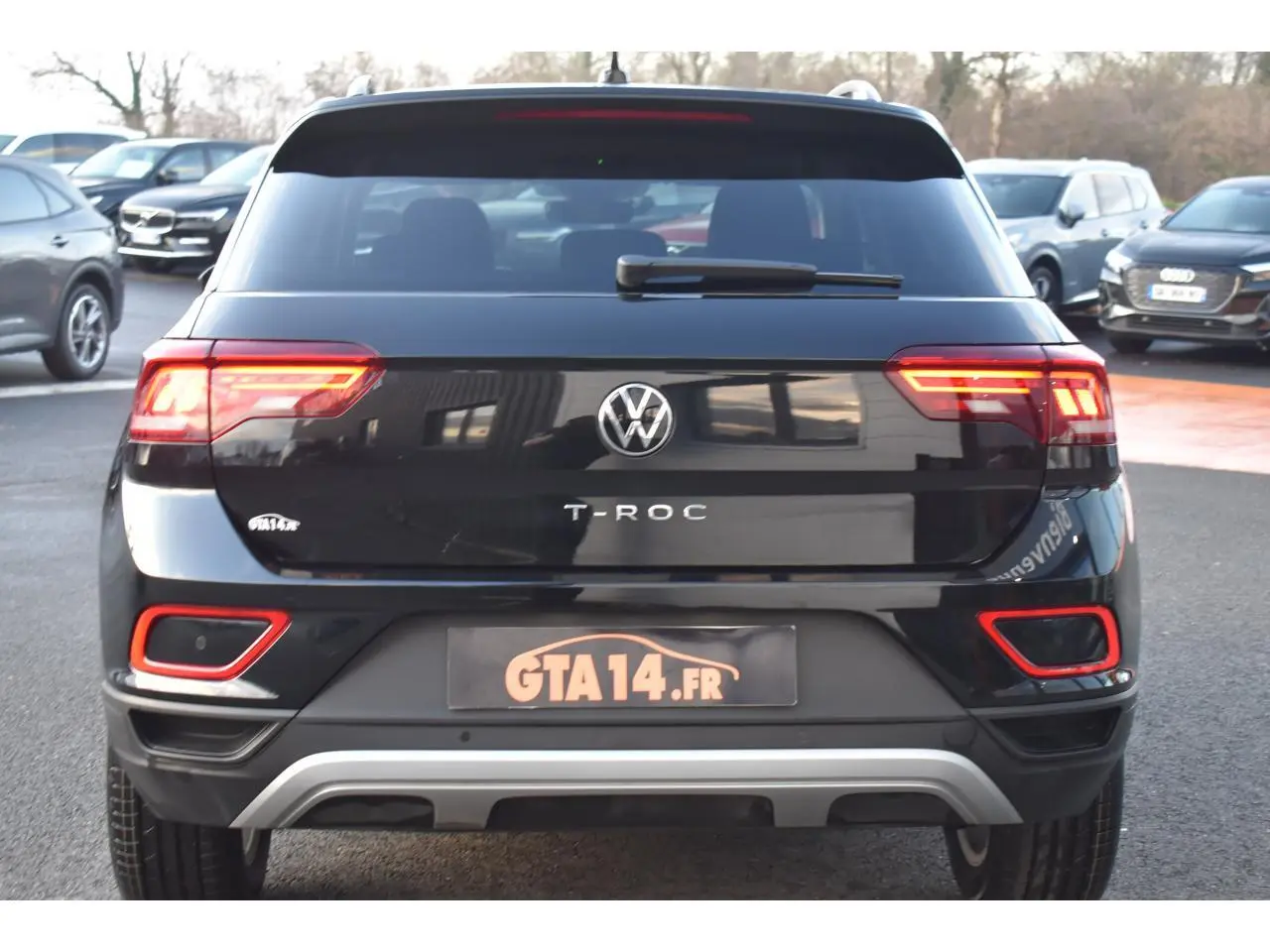 Vue arrière d'un Volkswagen T-Roc 2025 noir Grenadilla avec feux LED et détails rouges sur le pare-chocs.
