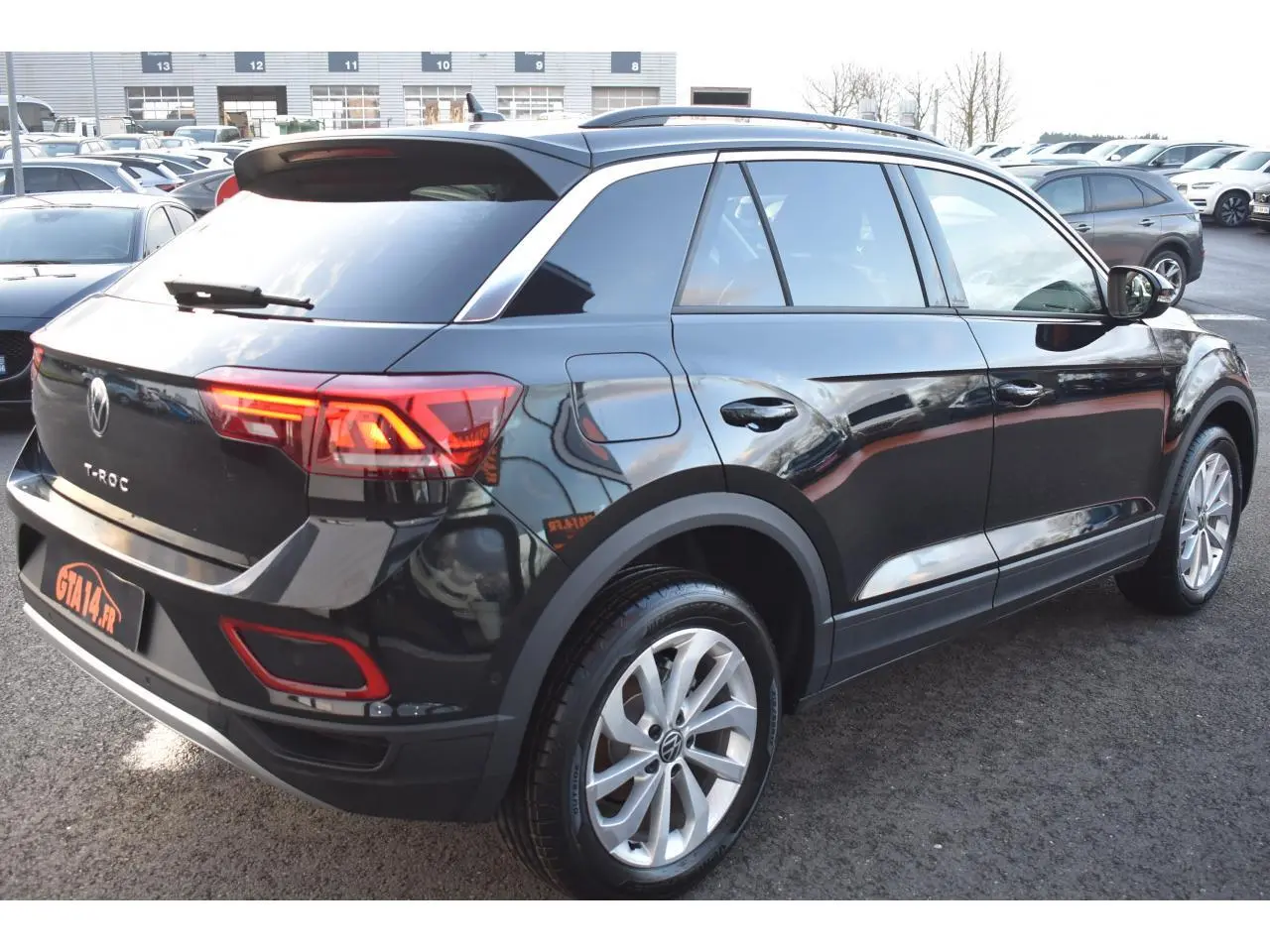 Volkswagen T-Roc 2025 noir Grenadilla, vue 3/4 arrière droit avec jantes alliage 17 pouces et feux LED allumés.
