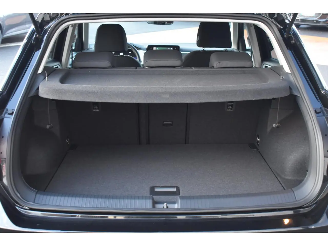Coffre ouvert vu de l'arrière du Volkswagen T-Roc noir Grenadilla, montrant l'espace de chargement et la plage arrière.