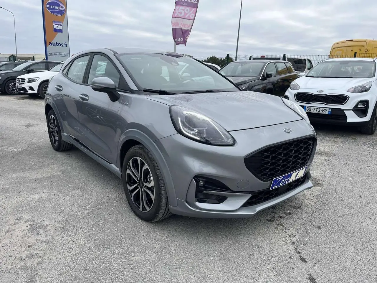 Ford Puma gris Solar vu en 3/4 avant droit sur un parking, avec calandre noire et jantes bicolores.
