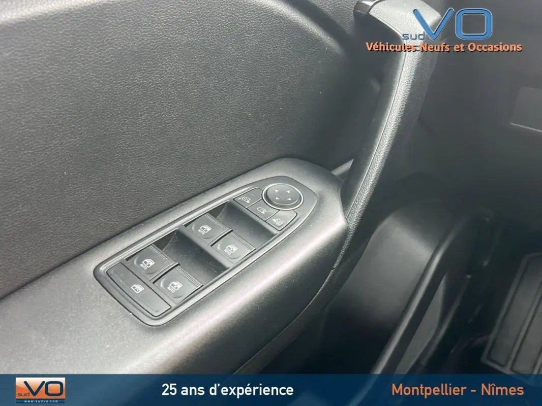 Gros plan sur les commandes des vitres électriques côté conducteur du Renault Captur gris Blue dCi 115 Business 2021.