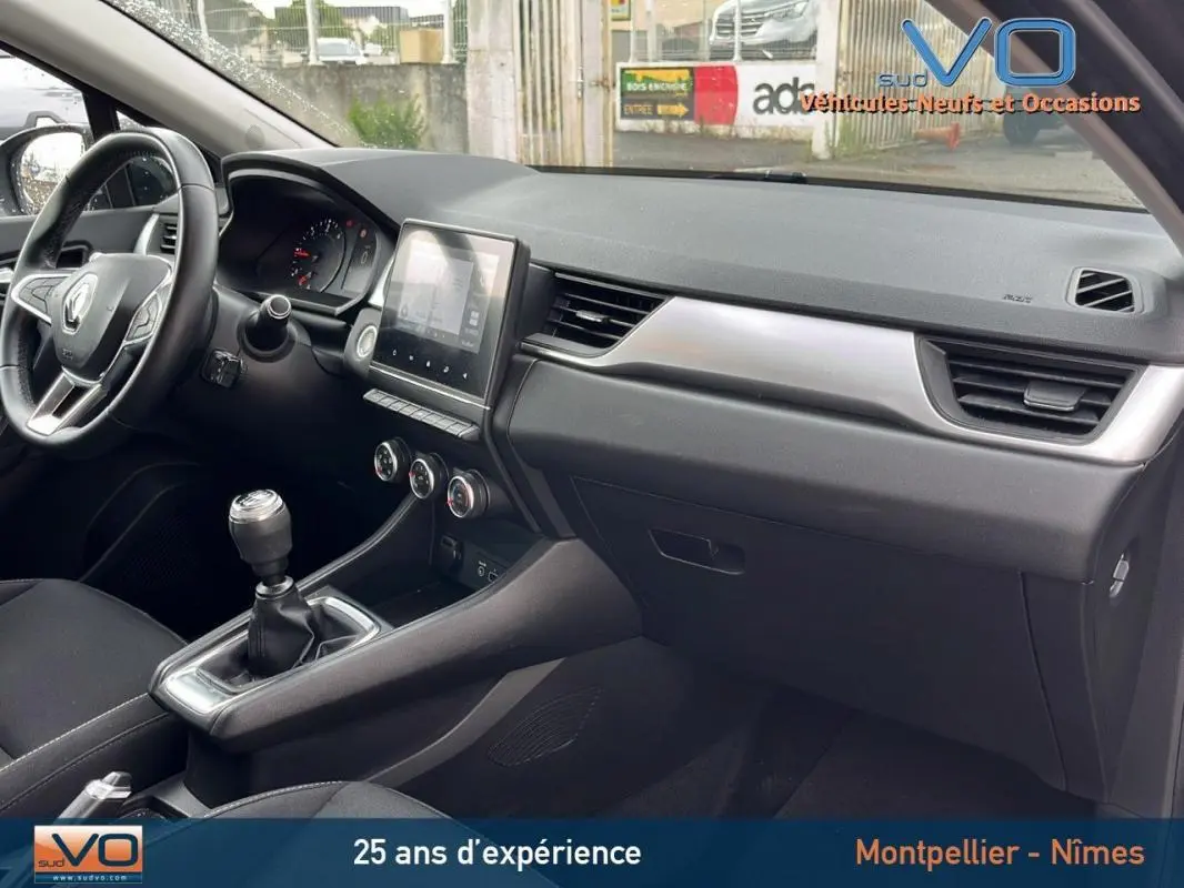 Intérieur côté passager du Renault Captur gris 2021, tableau de bord moderne avec écran tactile et boîte manuelle.