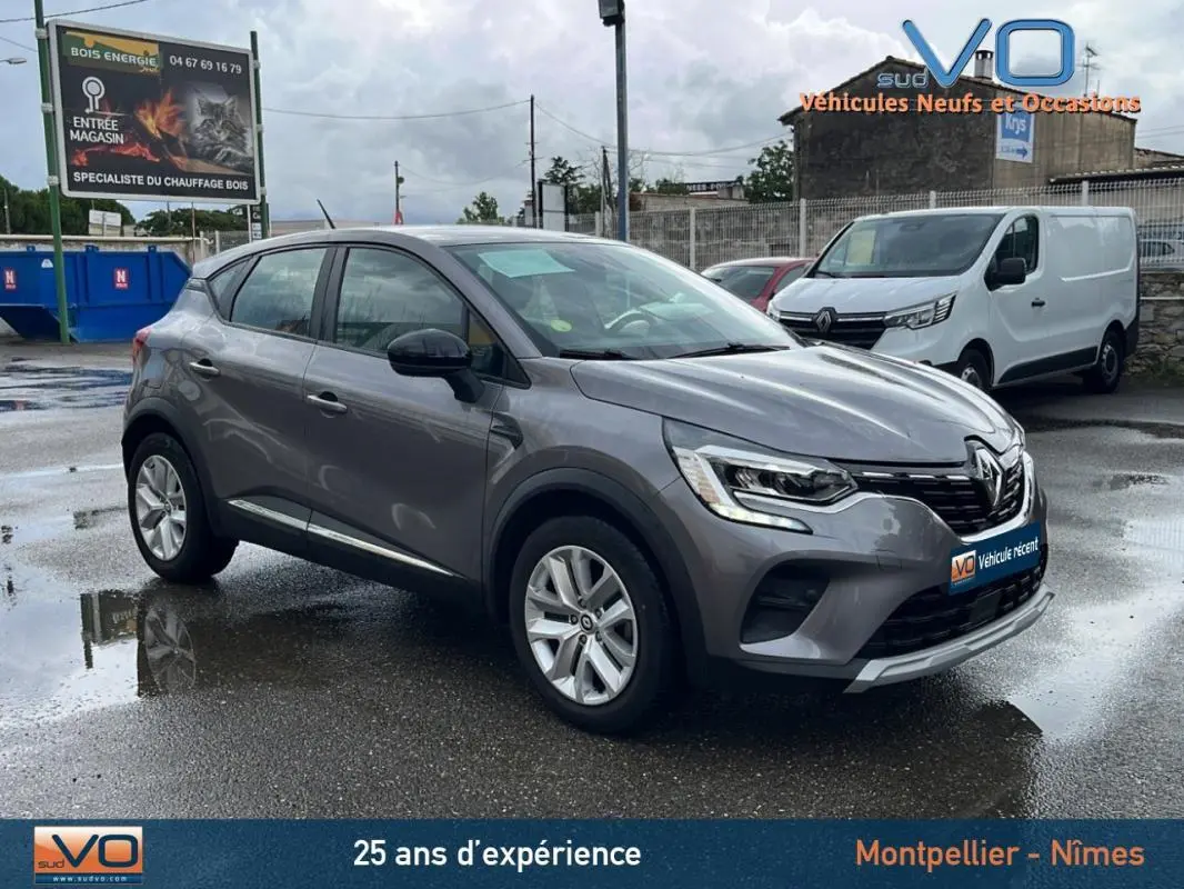Renault Captur Blue dCi 115 Business gris vu en 3/4 avant droit sur parking humide avec feux allumés