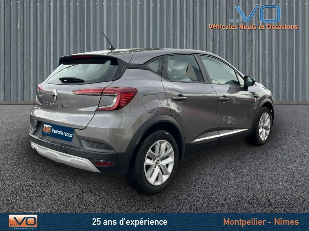 Vue 3/4 arrière droite d'un Renault Captur gris 2021 avec jantes alliage et feux arrière allumés.