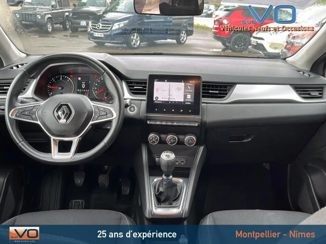 Vue intérieure avant du tableau de bord gris foncé du Renault Captur 2021 avec volant multifonction et écran tactile central.