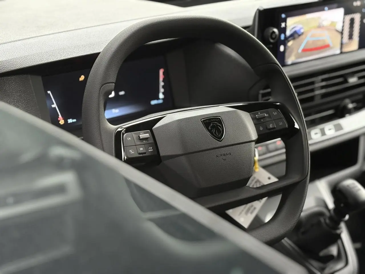 Vue rapprochée du volant Peugeot Expert Fourgon 2025 avec commandes intégrées et écran tactile affichant la caméra de recul.