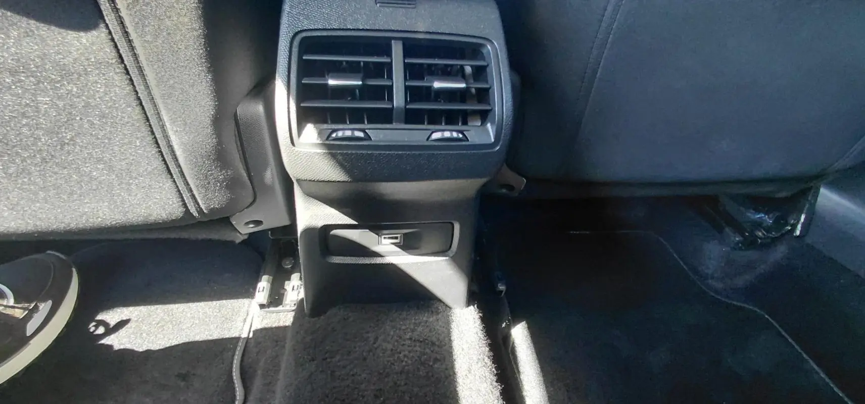 Vue rapprochée de la console arrière noire du Citroën C4 X hybride avec bouches d’aération et prise USB.