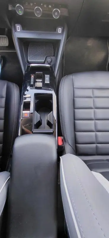Vue plongeante sur la console centrale noire et les sièges en cuir du Citroën C4 X Hybride 2025, avec accoudoir central.