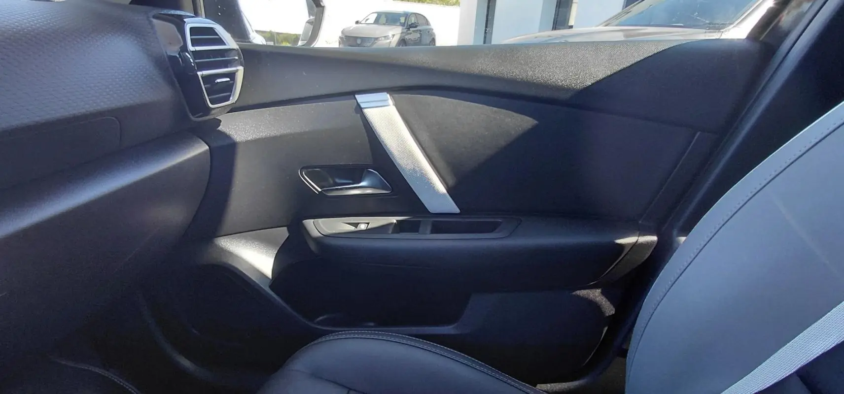 Vue intérieure côté droit de la porte et siège noir du Citroën C4 X hybride 2025 avec détails argentés.