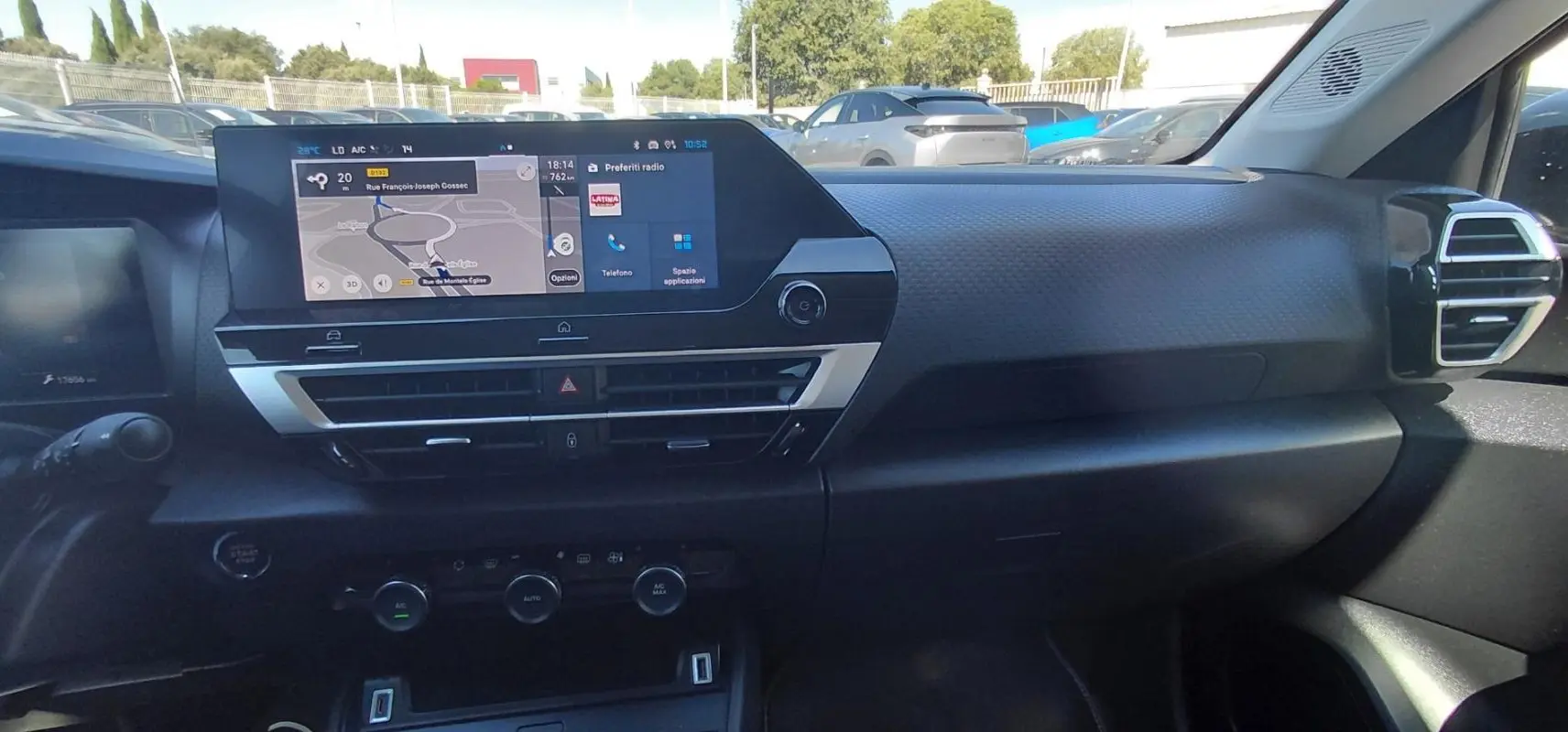 Vue intérieure du tableau de bord de la Citroën C4 X 2025, écran tactile central avec navigation et commandes climatisation.