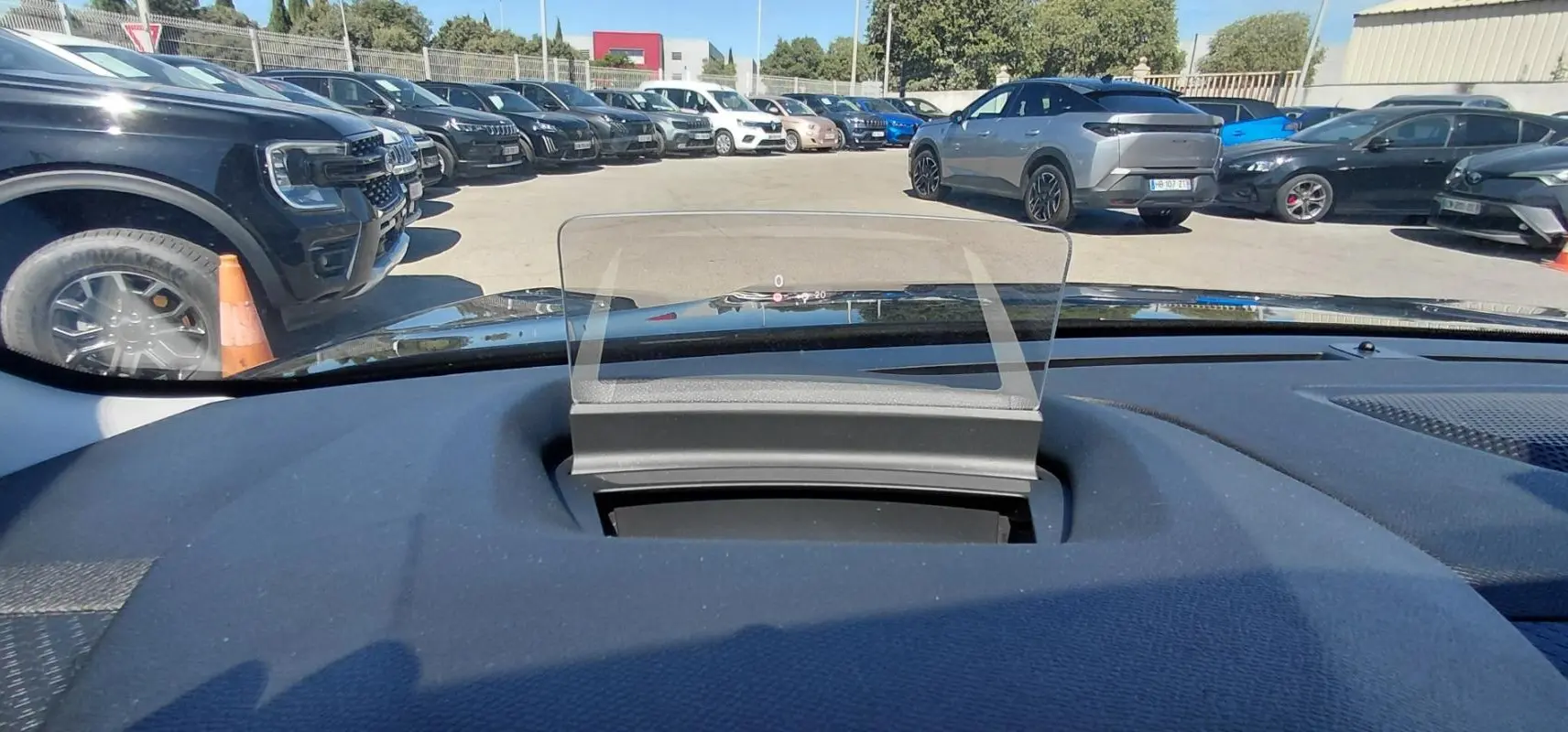 Affichage tête haute transparent sur le tableau de bord d’une Citroën C4 X noire, vue depuis l’intérieur vers l’avant.