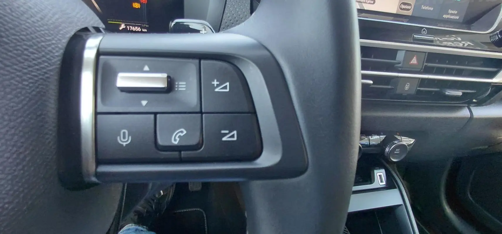 Gros plan sur les commandes gauche du volant cuir de la Citroën C4 X noire, avec tableau de bord et console en arrière-plan.