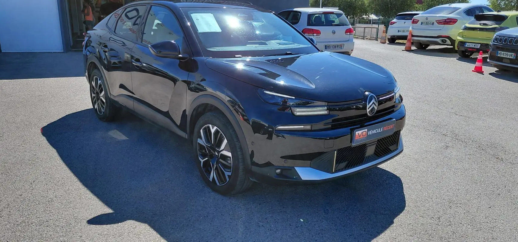 Citroën C4 X hybride noir vue 3/4 avant droit, avec jantes alliage 17 pouces et toit ouvrant panoramique.