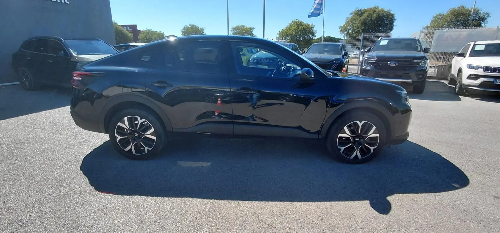 Vue de profil côté gauche d'une Citroën C4 X noire 2025 avec jantes alliage 17 pouces sur parking extérieur.