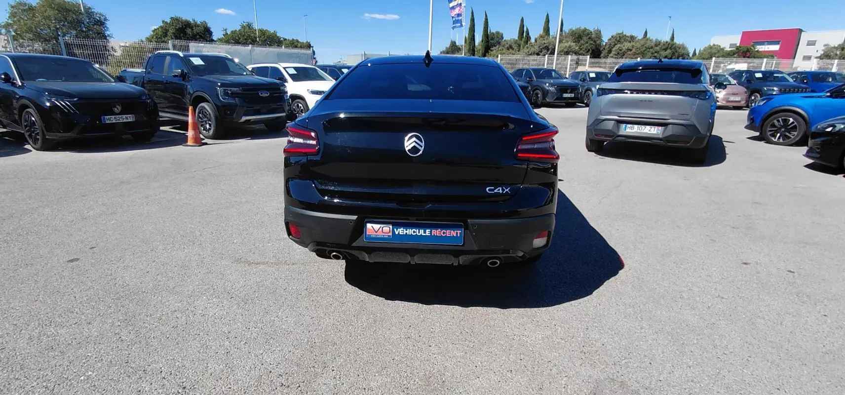 Vue arrière d'une Citroën C4 X noire 2025 avec feux LED et double sortie d'échappement visible en parking.