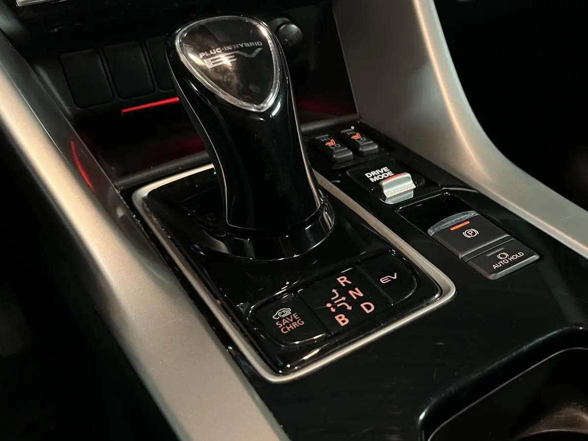 Gros plan sur le levier de vitesse noir brillant du Mitsubishi Eclipse Cross hybride rechargeable, avec commandes autour.