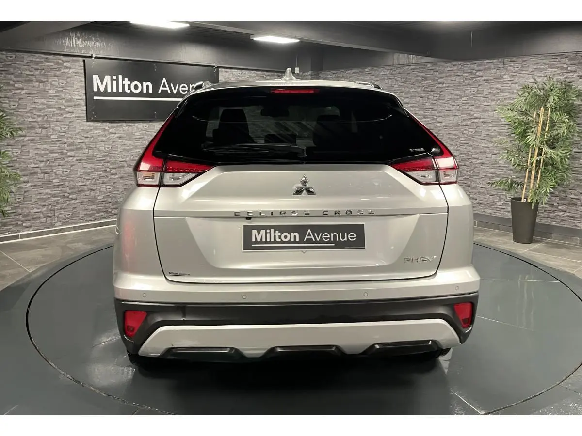 Vue arrière du Mitsubishi Eclipse Cross gris métallisé avec feux LED et logo PHEV visible en intérieur showroom