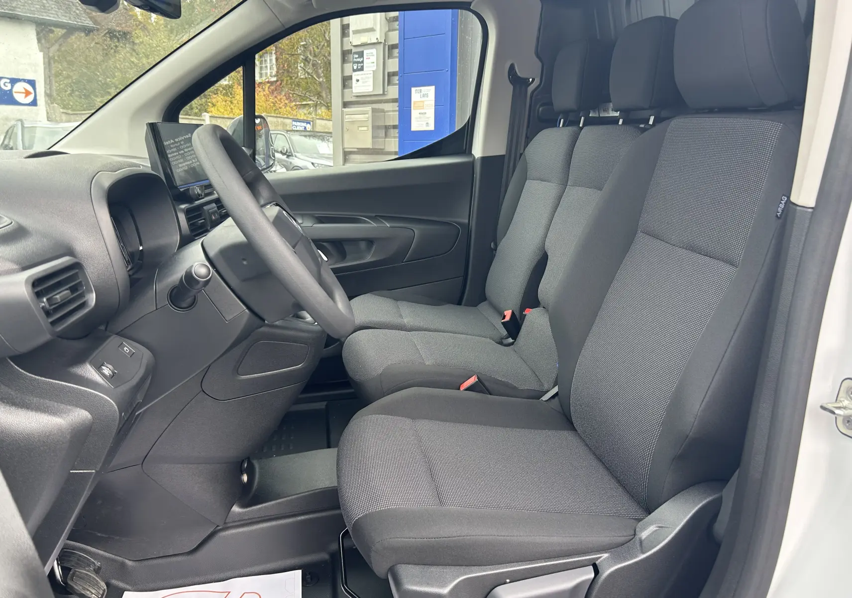 Intérieur du Citroën Berlingo Fourgon blanc 2025, vue côté conducteur montrant les sièges tissu et le tableau de bord.