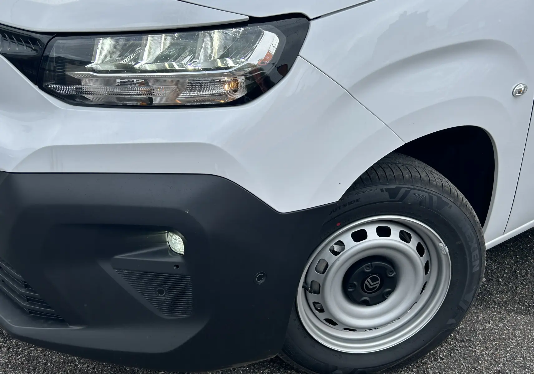 Gros plan sur l'avant droit blanc du Citroën Berlingo Fourgon 2025 avec phare LED et jante acier simple.