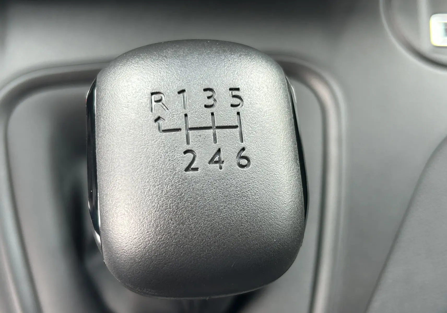 Gros plan sur le levier de vitesses manuel noir du Citroën Berlingo Fourgon blanc, montrant la grille à 6 rapports plus marche arrière.