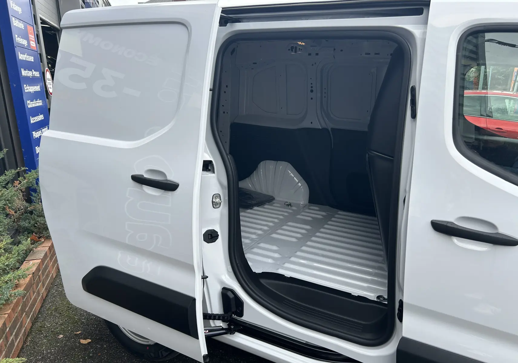 Vue latérale gauche d'un Citroën Berlingo Fourgon blanc avec porte coulissante ouverte dévoilant l'espace de chargement vide.