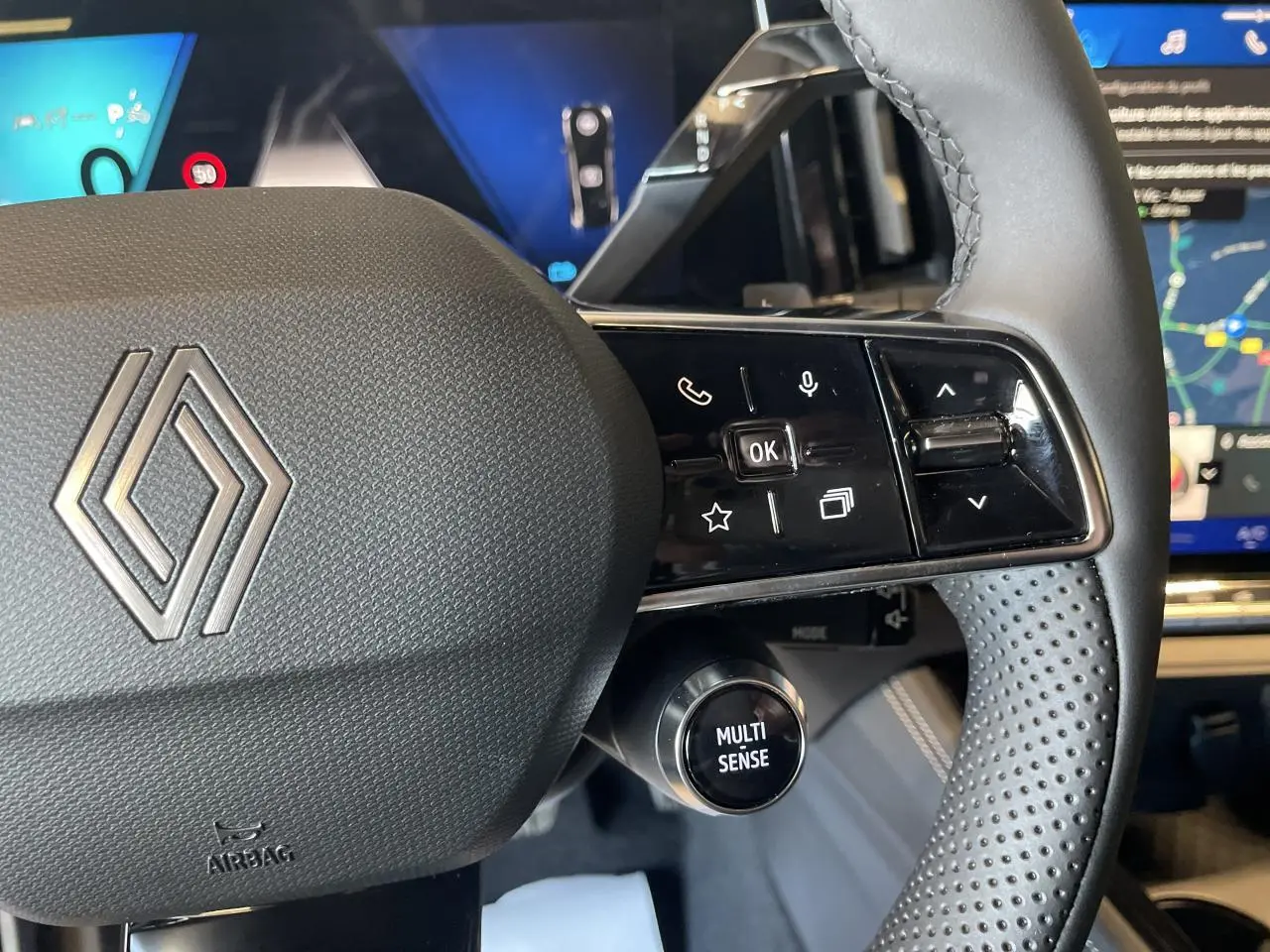 Gros plan sur le volant noir perforé de la Renault Rafale 2025 avec commandes et bouton Multi-Sense visible.