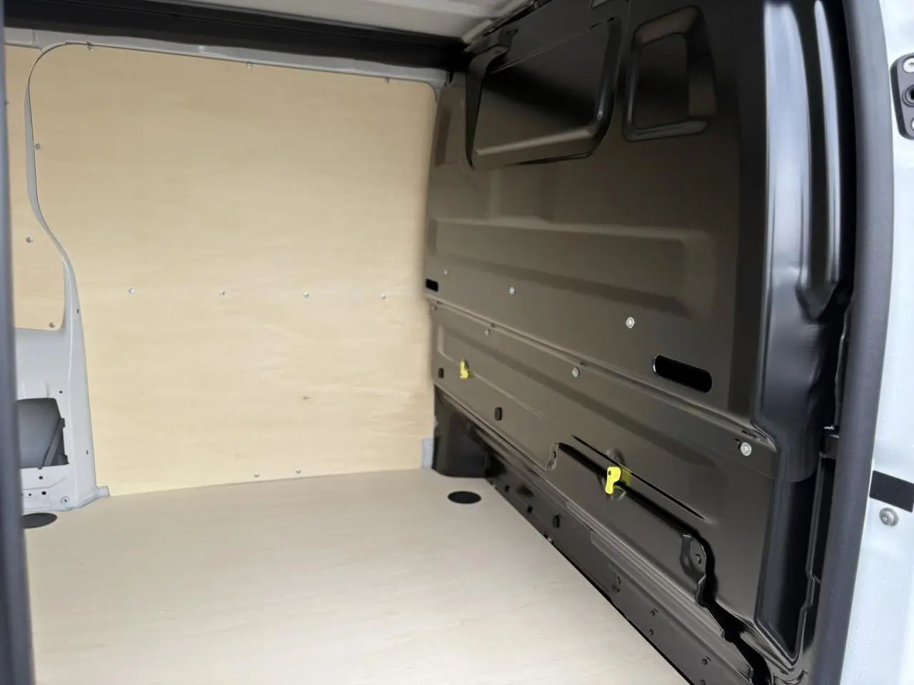 Vue intérieure de la zone de chargement du Peugeot Expert Fourgon blanc Icy, avec cloison bois et paroi latérale noire.